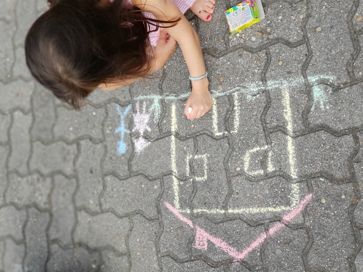 Ein Kind zeichnet mit Kreide auf dem Boden.